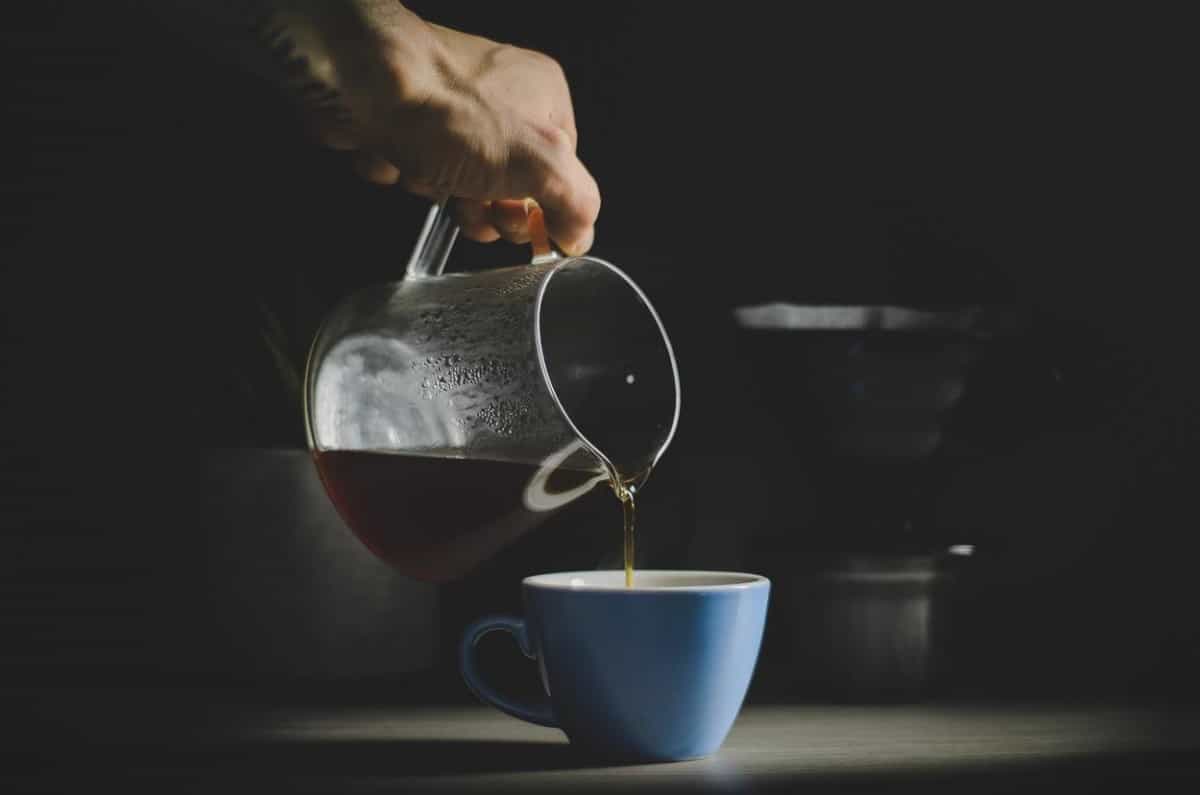 A cup of coffee being poured into a mug. 
