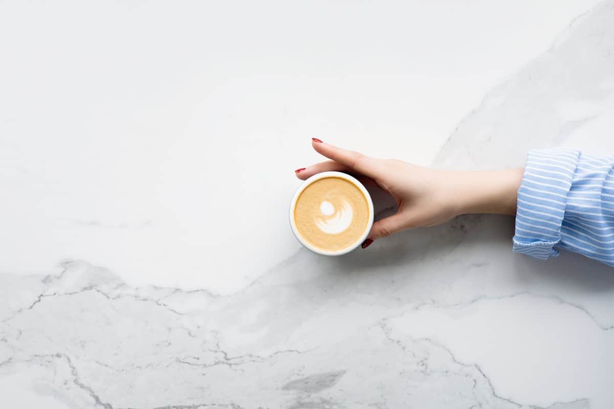 An image of a woman's hand reaching for the coffee