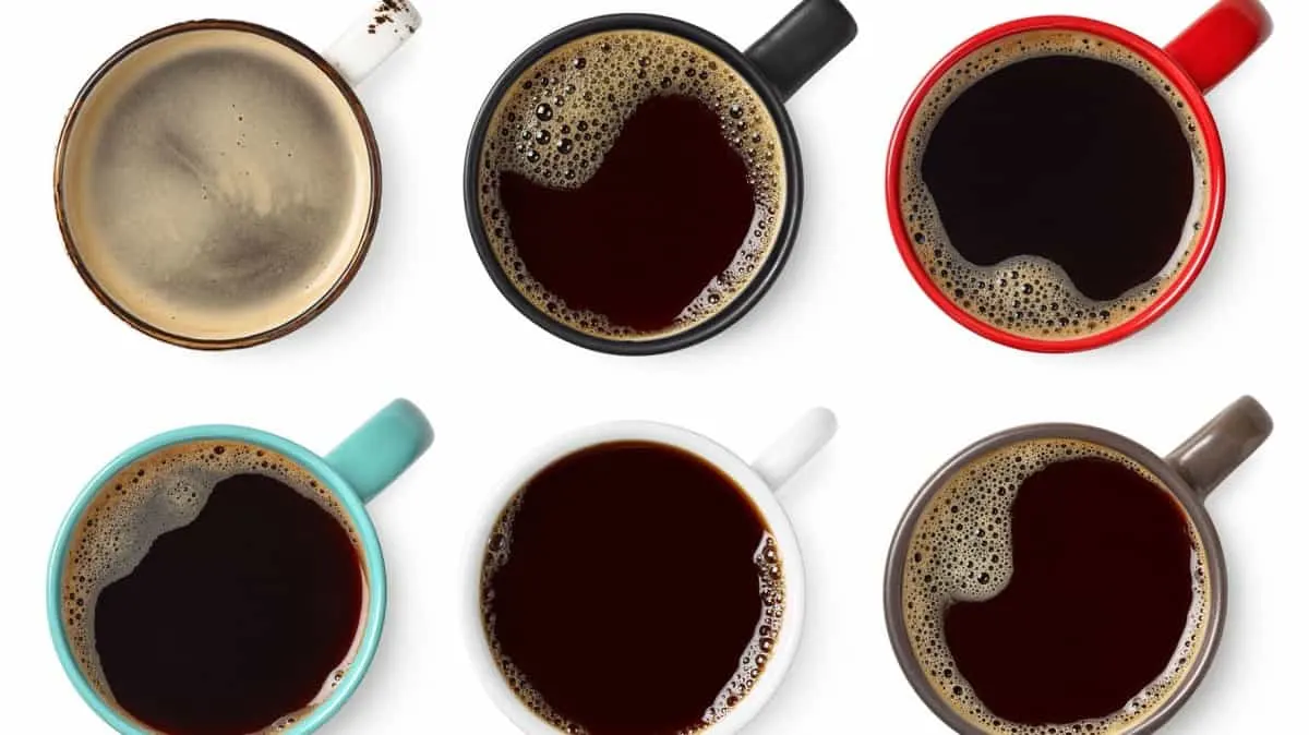 An above view of coffee in different colored mugs
