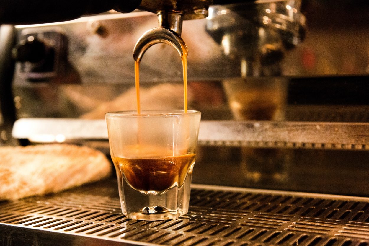 A strong shot of espresso just coming out of an espresso machine.