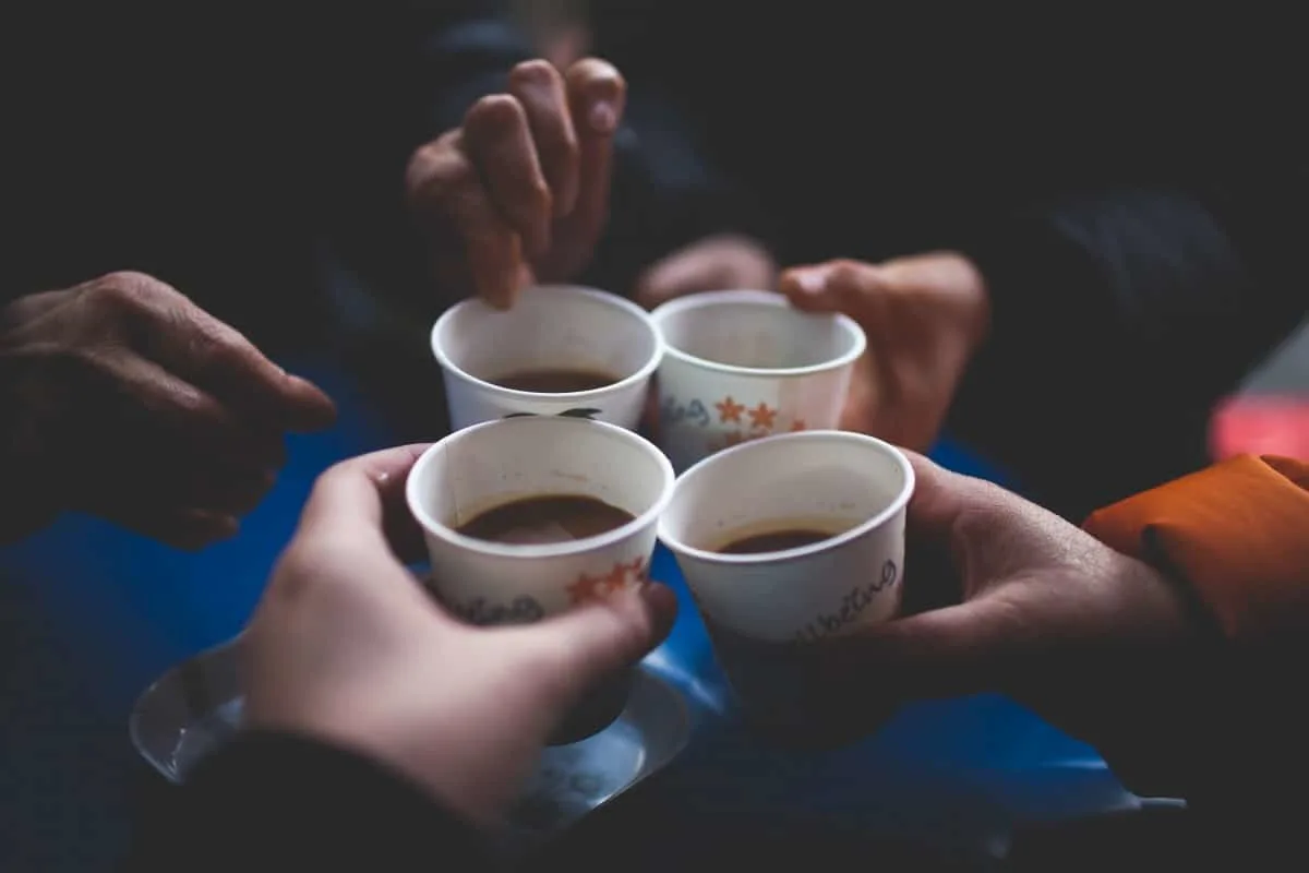 four people toasting to four cups of coffee