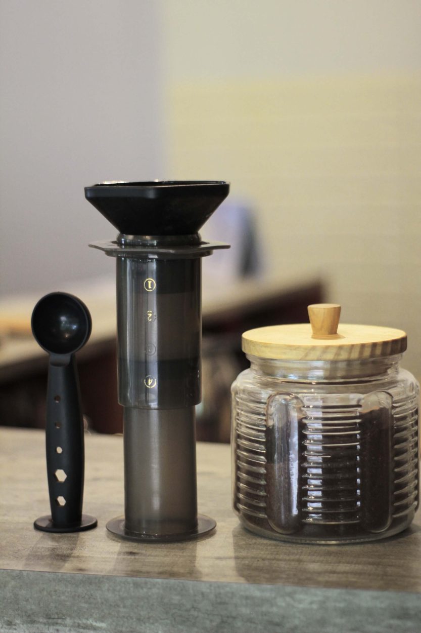 a dismantled Aeropress with a pot of coffee grounds.