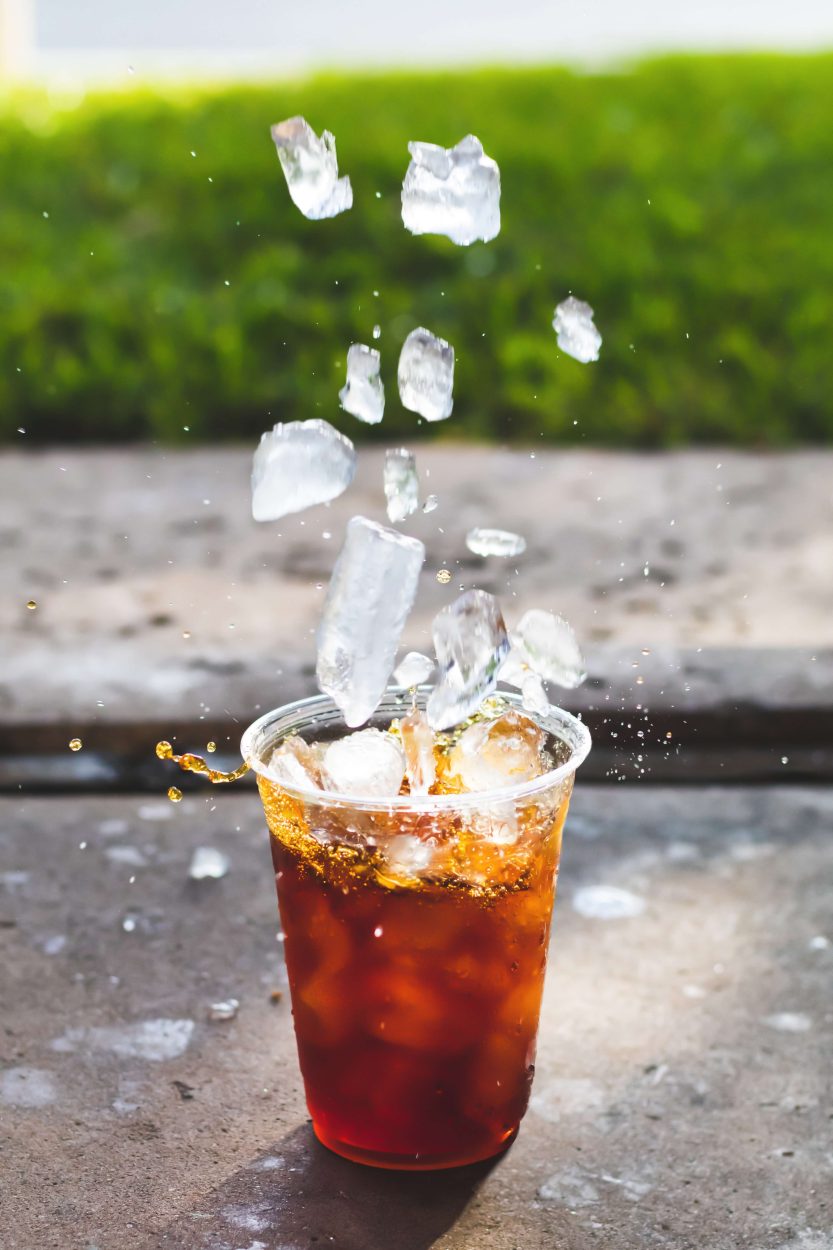 A plastic cup of Kyoto cold brew getting splashed with ice. 