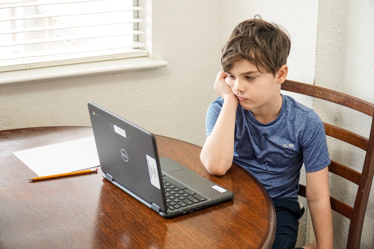 a kid is irritated while taking his online class