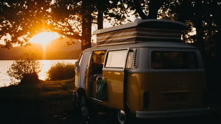 A yellow van under a tree during sunset.