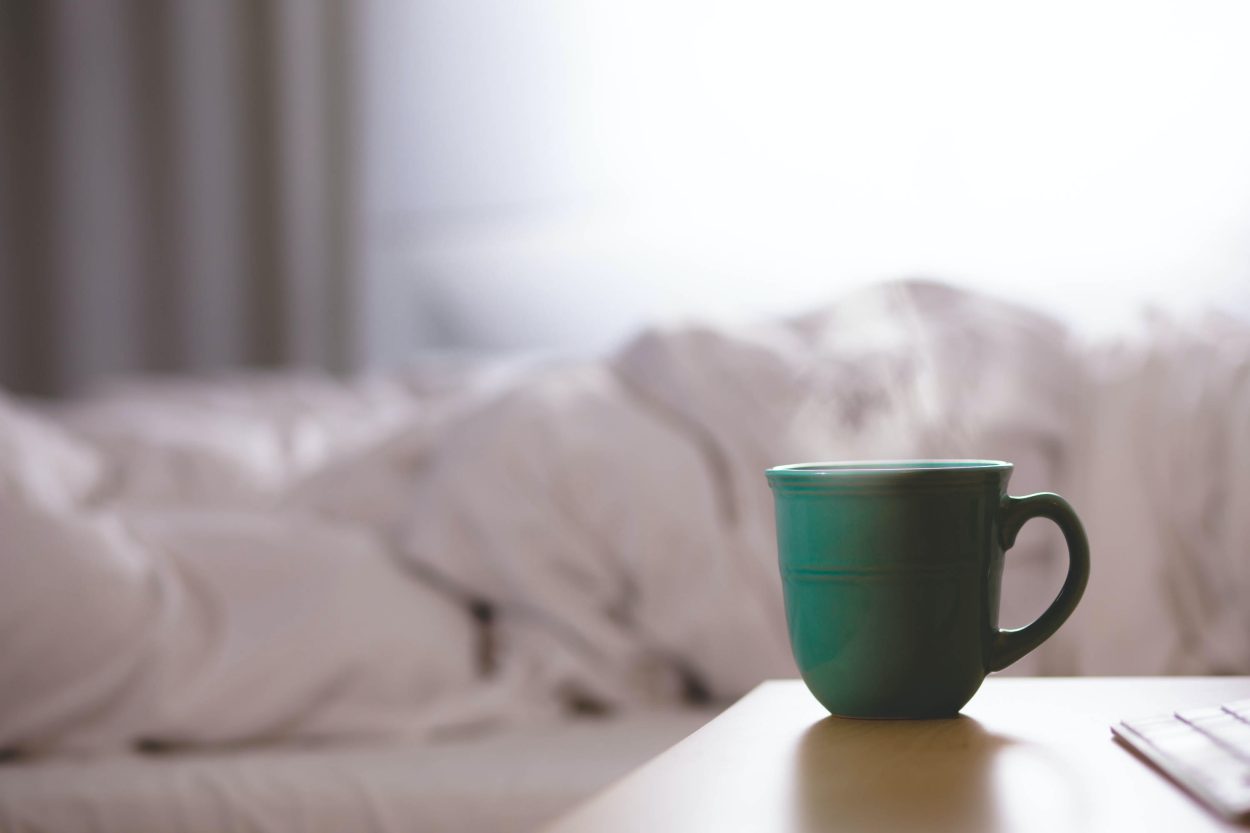 a coffee mug next to a bed