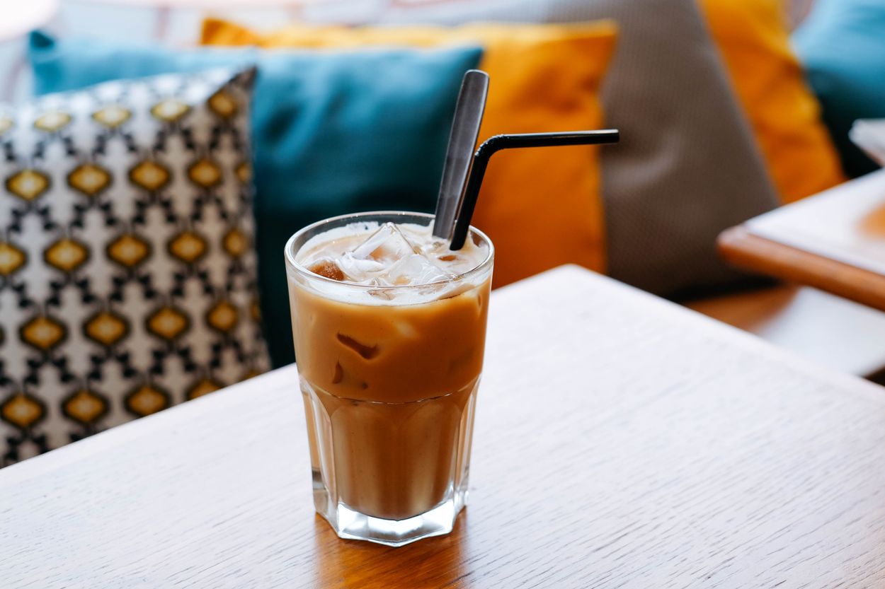 an iced coffee with a straw sitting on a table 