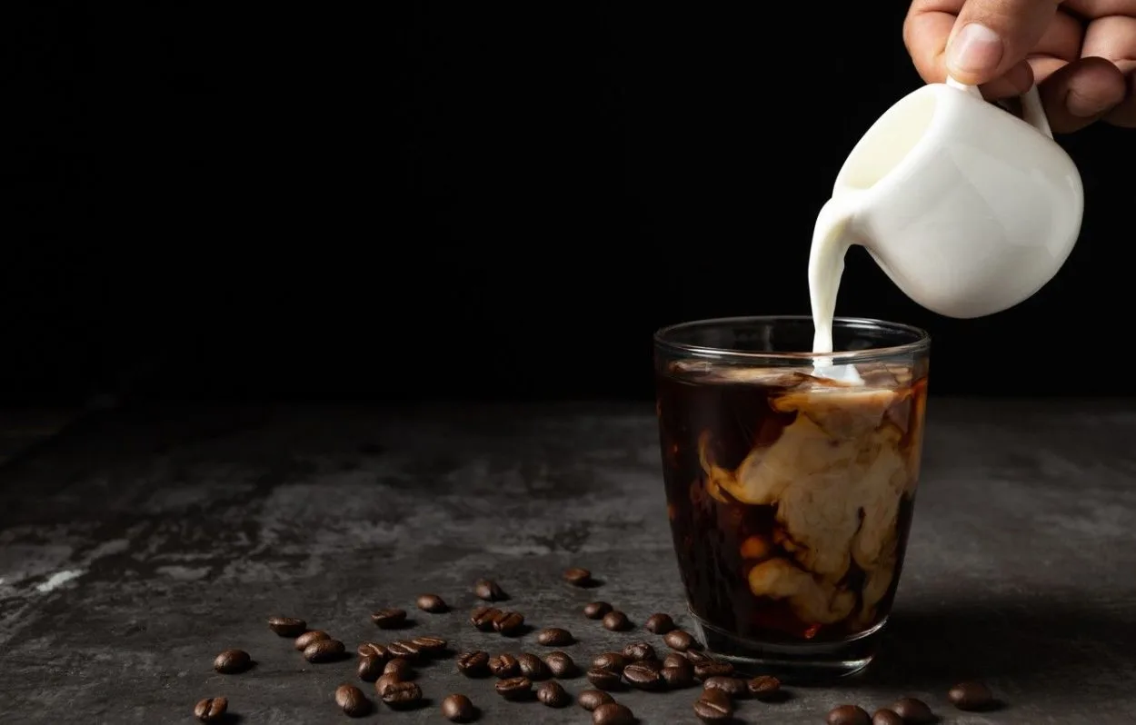someone pouring milk into coffee