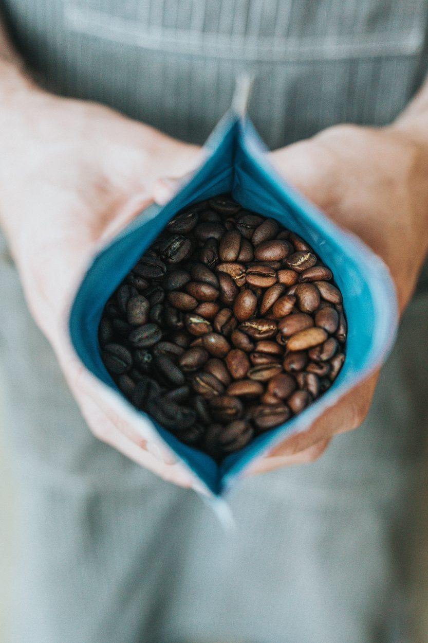 a opened bag of coffee beans in a person's hand