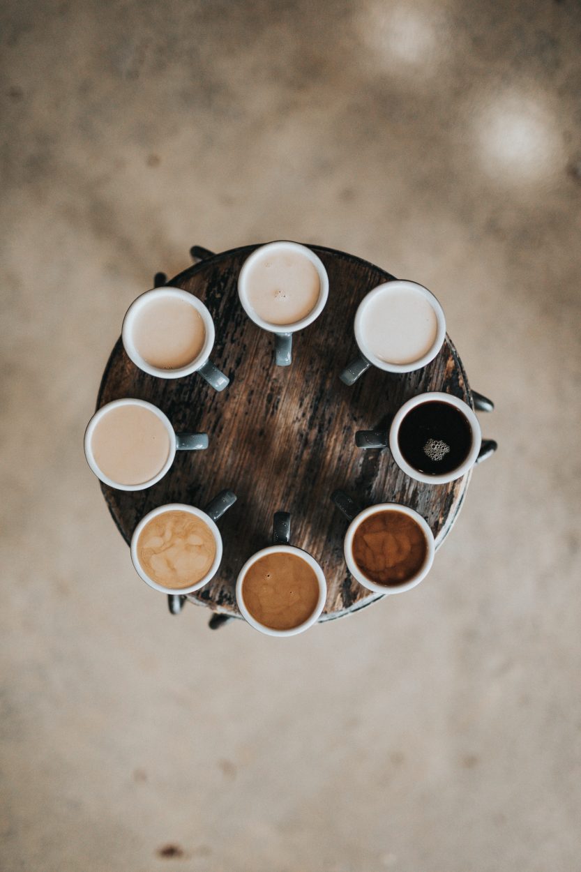 Different kinds of coffee drinks arrange in a circle atop a round small table.