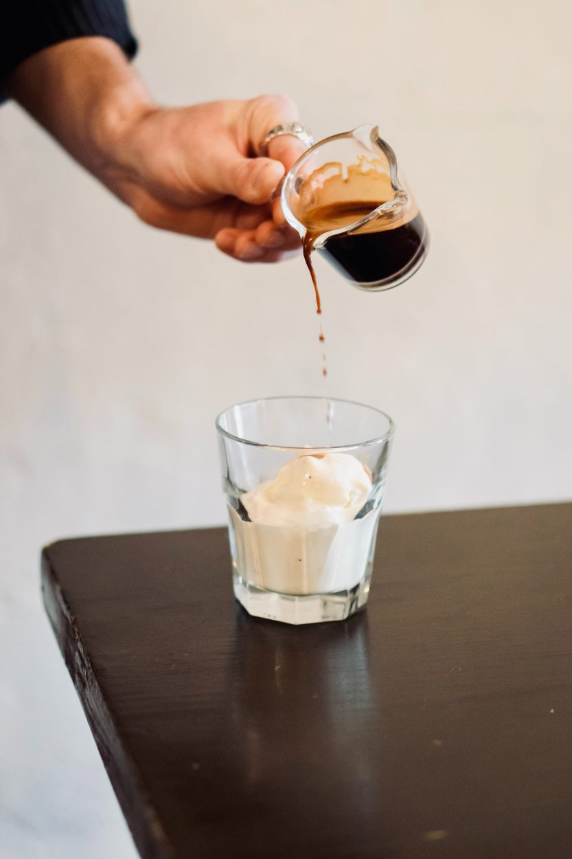 An espresso shot being poured over vanilla ice cream.