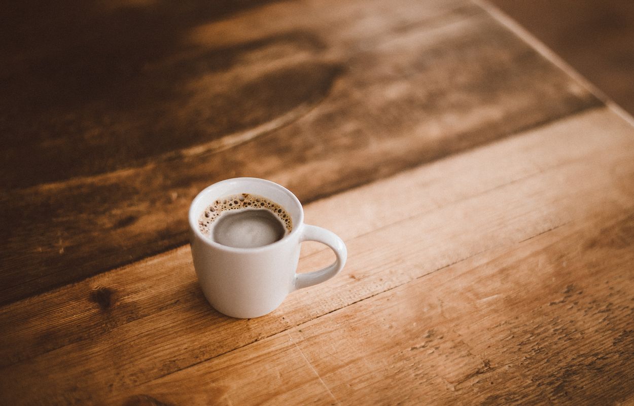 cup of black coffee on a hard wood floor