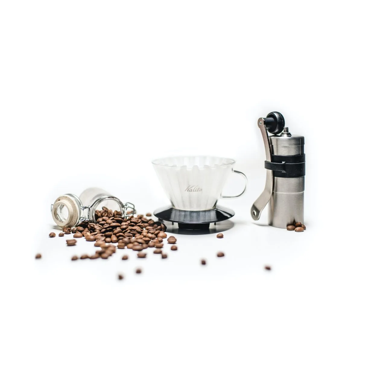 a coffee grinder next to a cup and a spilled jar of coffee beans