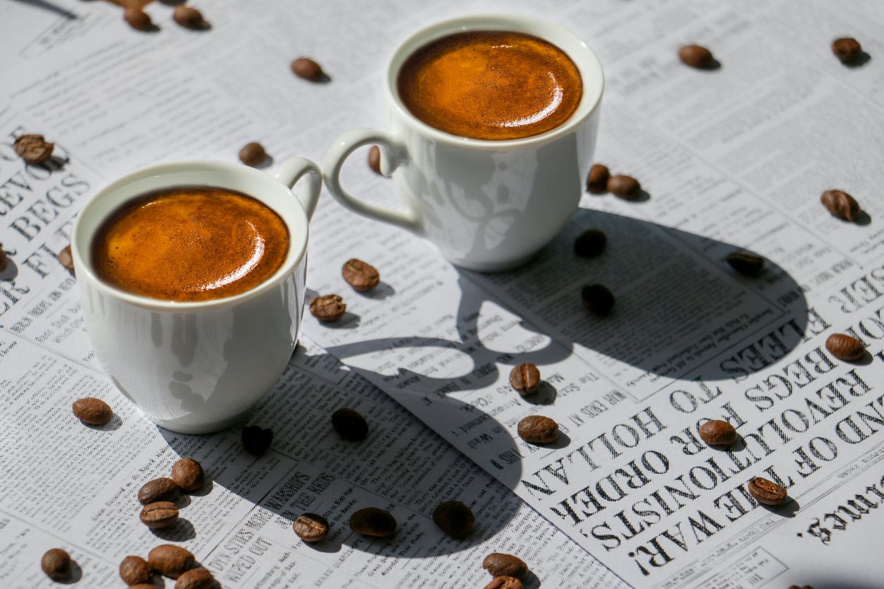 two cups of coffee on top of a newspaper