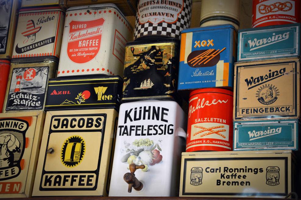 Different brands of private label organic coffee tin cans stacked up on top of each other.