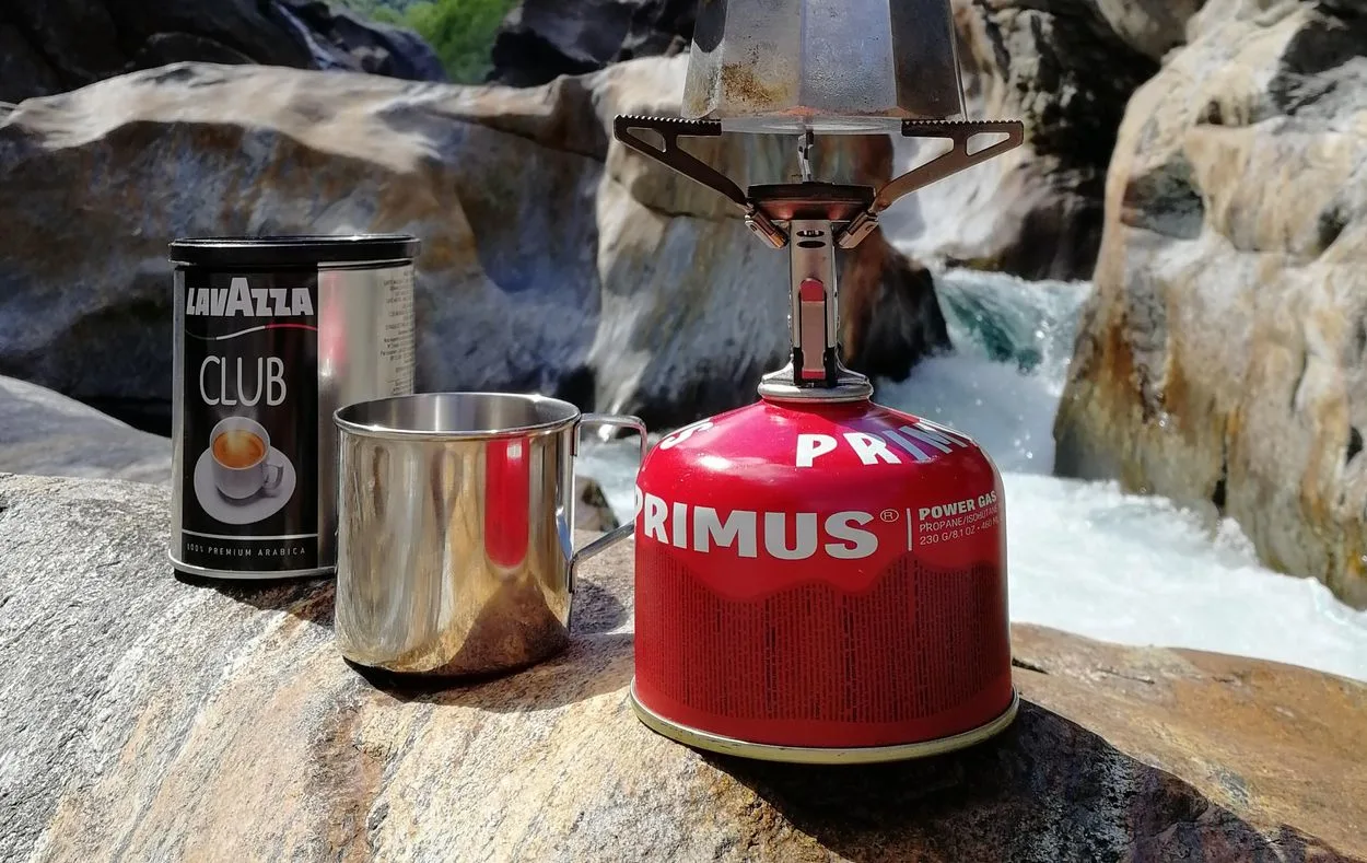  a can of Lavazza espresso powder next to a tin cup and a Moka pot