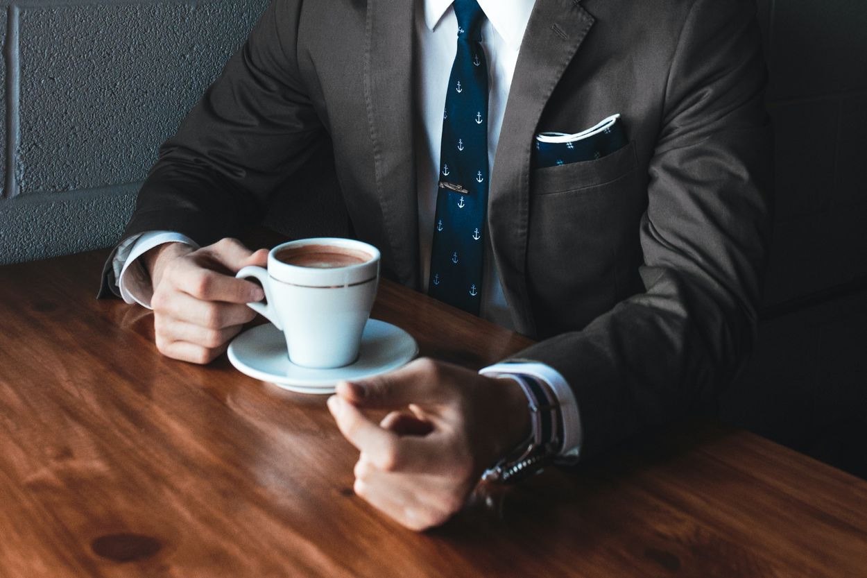 a person in a suit having a cup of coffee