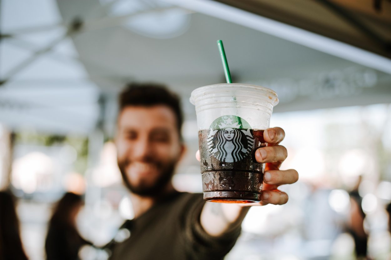 A barista holding a to-go iced coffee cup.
