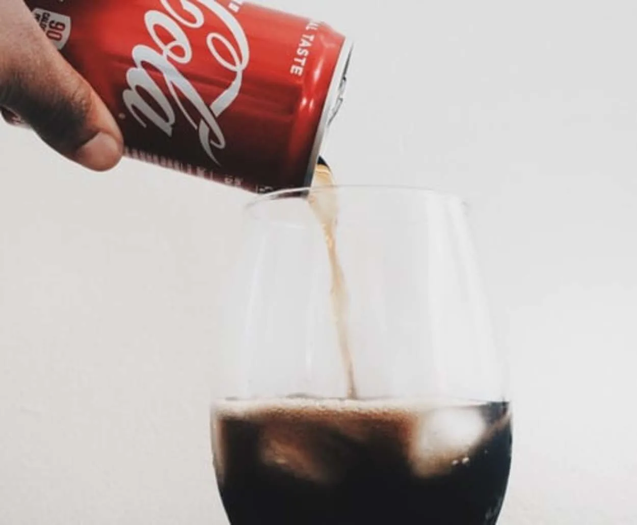 A can of Coke being poured into a glass
