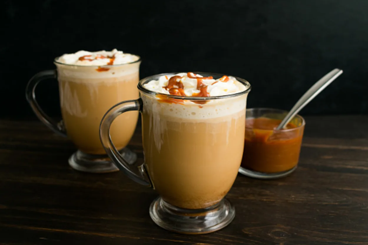Coffee with milk topped with whipped cream and caramel sauce
