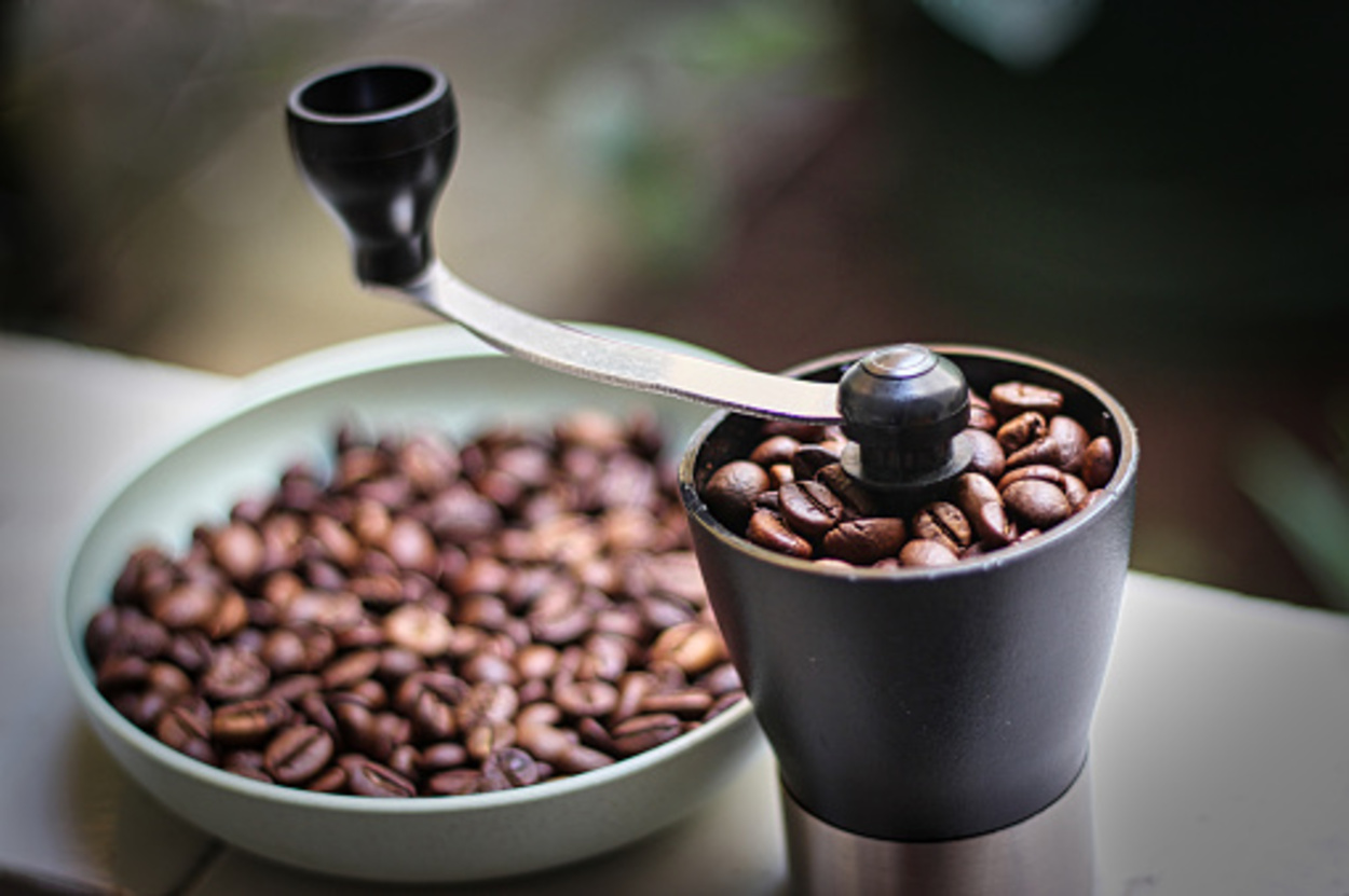 coffee beans in a cup and a coffee grinder on the porch of the house in the afternoon