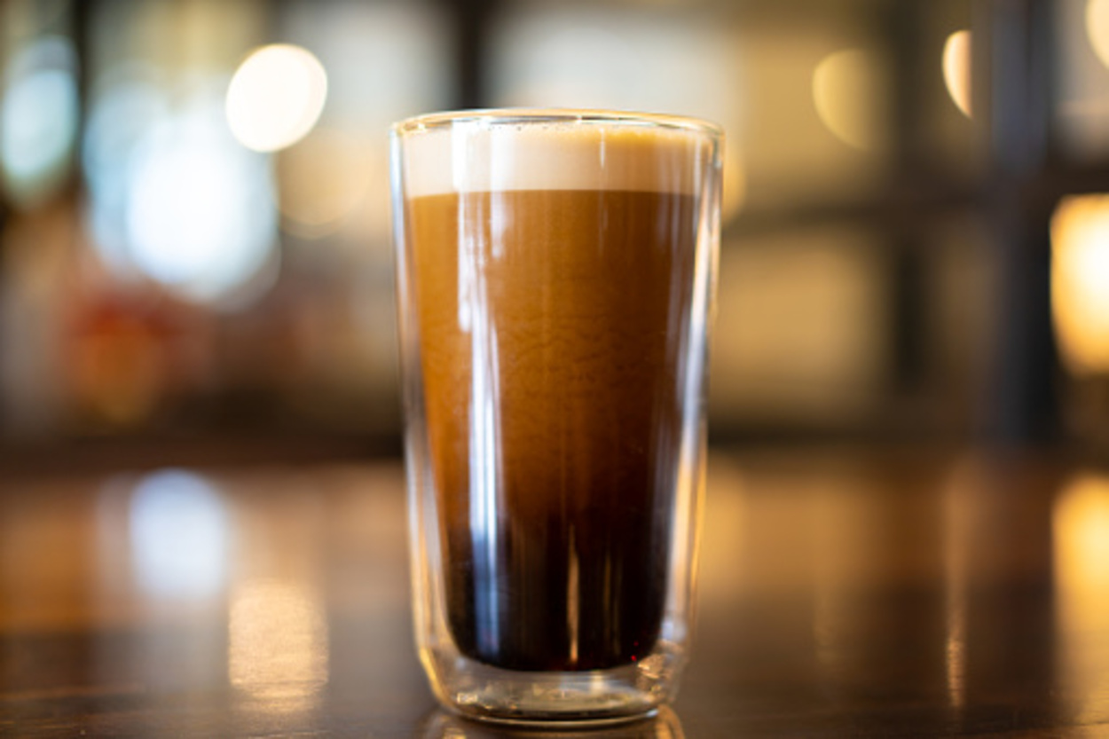 Beautiful texture and layers of Nitro Cold Coffee served in a double wall glass close up.
