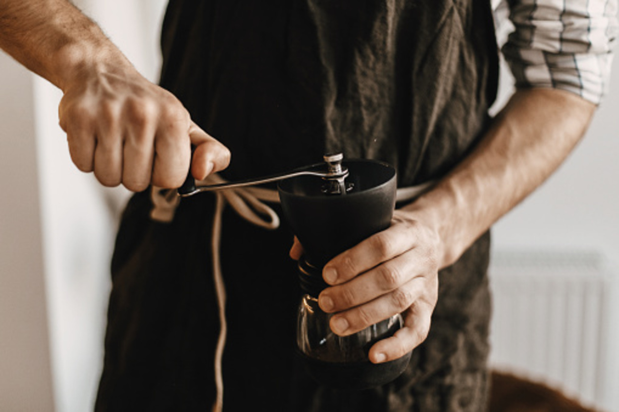 Barista grinding coffee in hand grinder