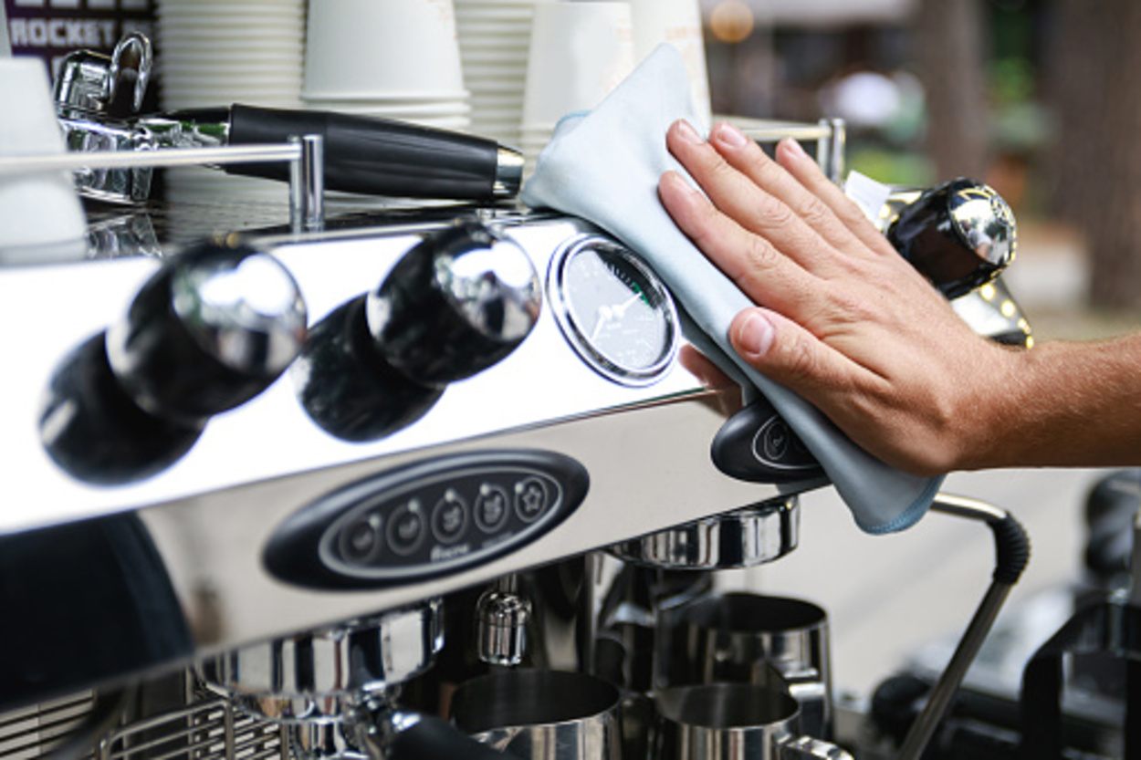 Barista man cleaning espresso machine after working day