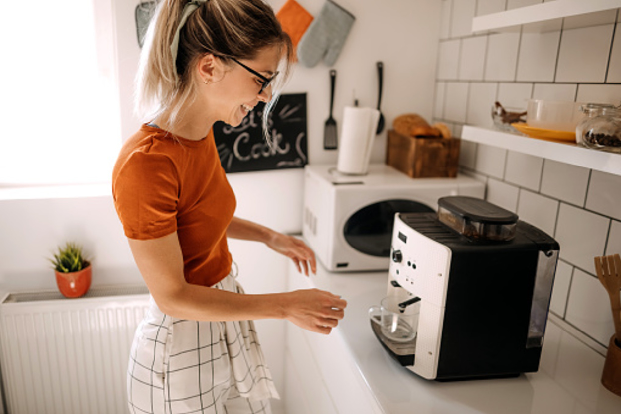 Young woman making coffee on coffee machine at home