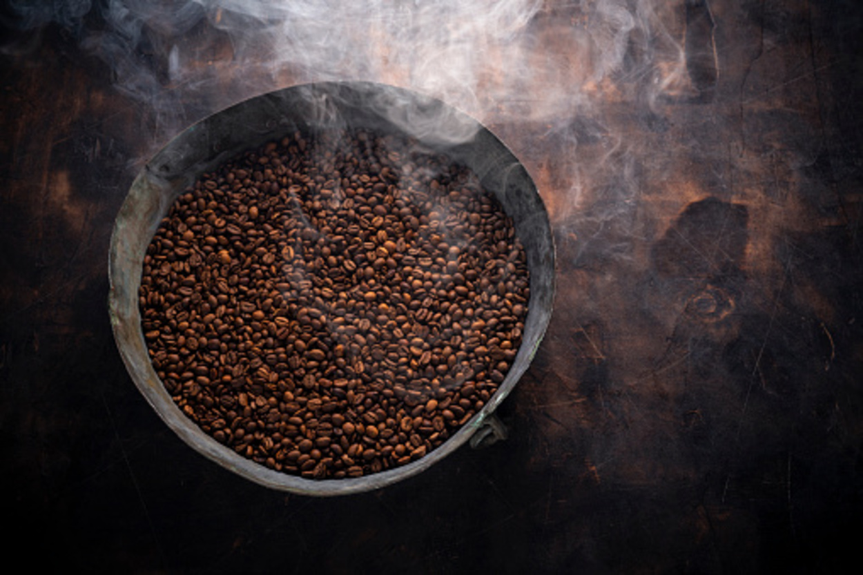 Medium roasted coffee beans smoking in a roasting pan