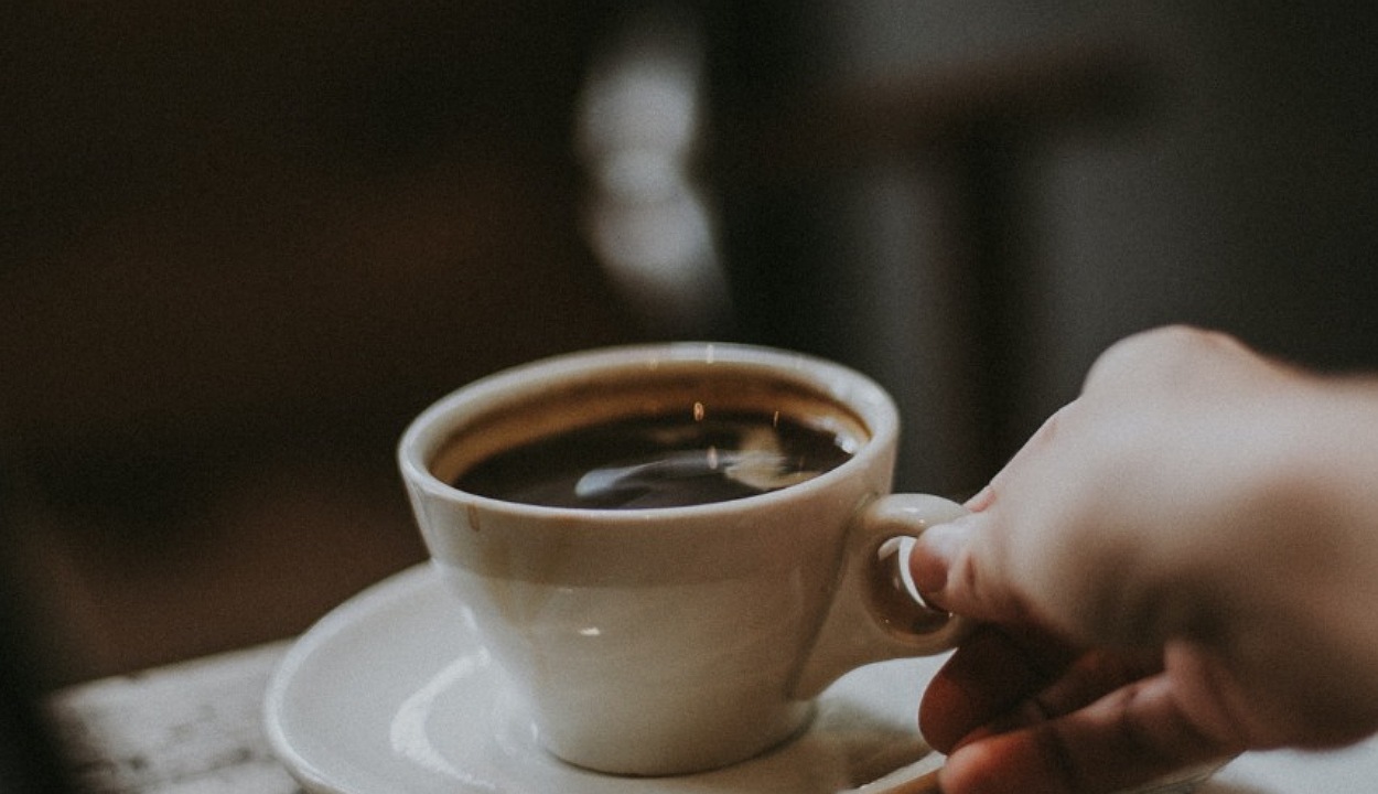 An image of cup of coffee held by a person.