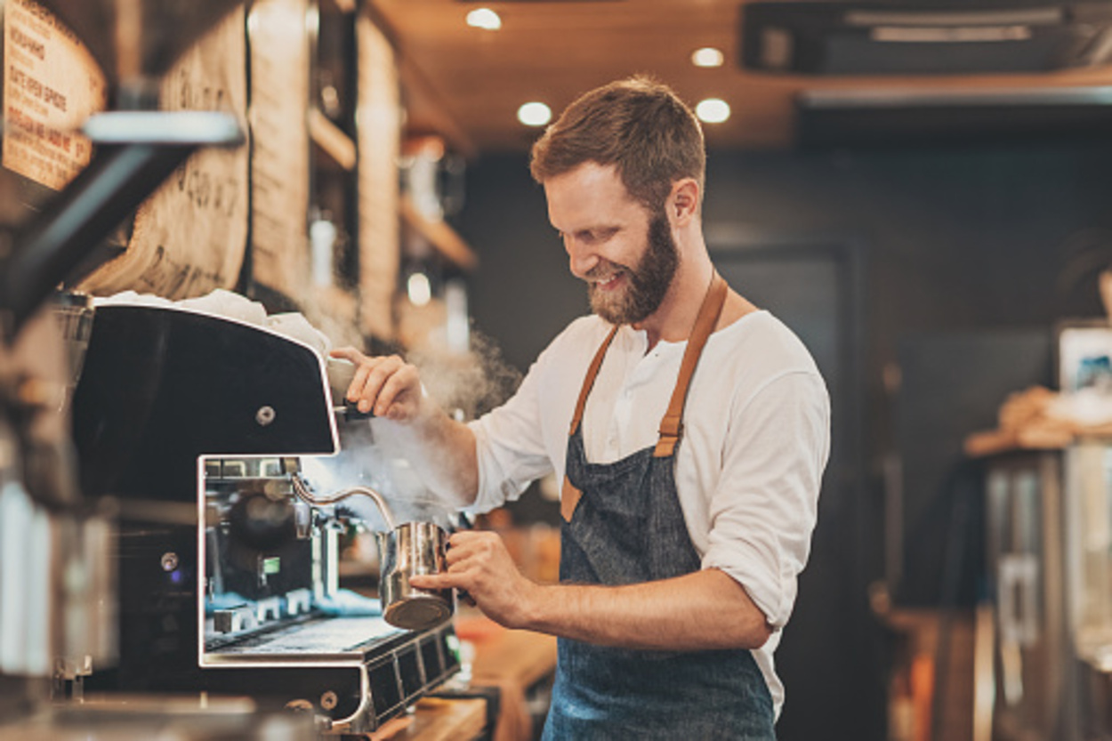 male barista preparing cappuccino in a coffee shop