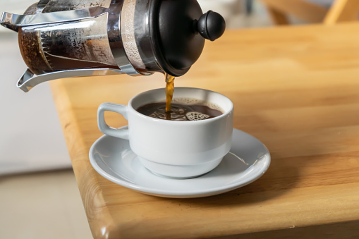 Pouring French press coffee into a cup on a table