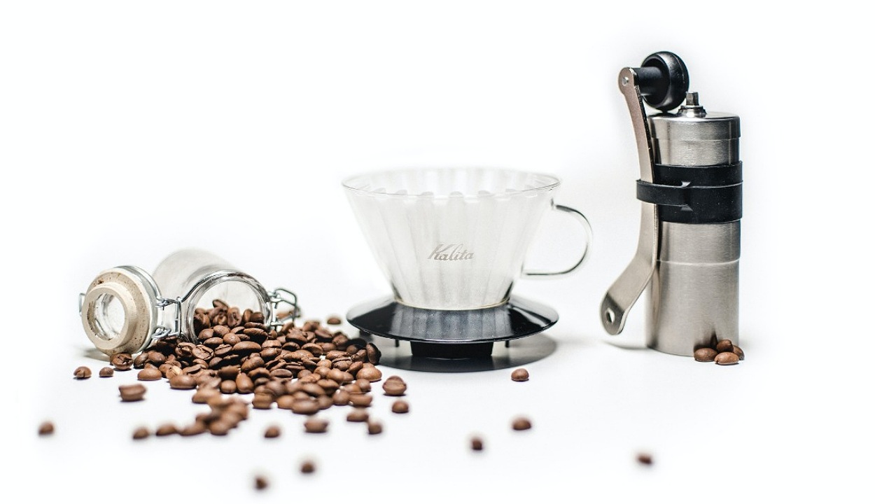 Image of coffee grinder, a cup and coffee beans.