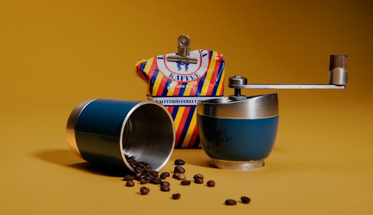 Image of manual coffee grinder and coffee beans placed with in it.
